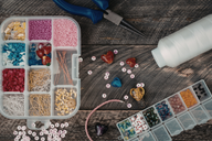 Overhead view of colorful beads, jewelry-making supplies, and tools on a wooden surface