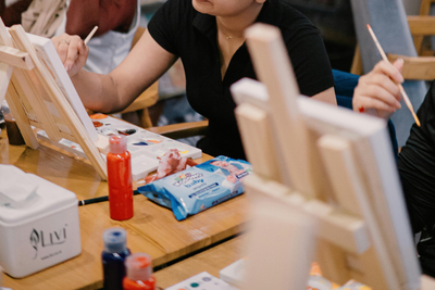 Group of people painting on small canvases together at a workshop table
