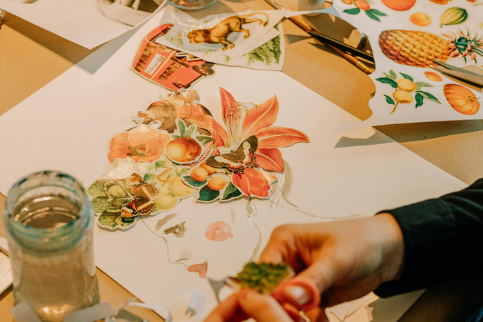 Hands creating a botanical collage artwork with cut-out illustrations and watercolors